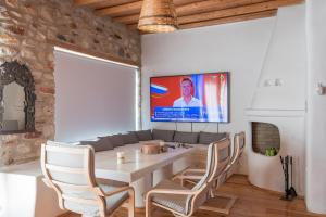 ein Esszimmer mit Tisch und Stühlen und einem Fernseher in der Unterkunft Villa Cornelia in Aliki