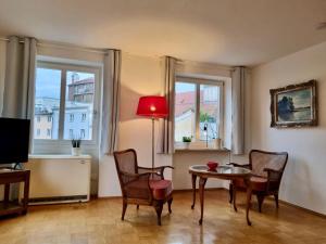 a living room with a table and chairs and two windows at Ferienwohnung Dreierlei in Wasserburg am Inn