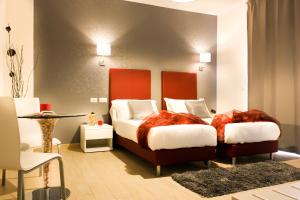 a bedroom with two beds and a table and chairs at Hotel Rossovino Como in Como
