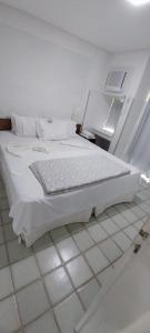 Cama blanca en habitación con suelo de baldosa en Ancorar flat resort- porto de galinhas, en Porto de Galinhas