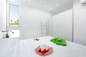 1 dormitorio con 1 cama con sombrero y toallas verdes en Chic apartment with great terrace, en Playa de las Américas 33 fotos más