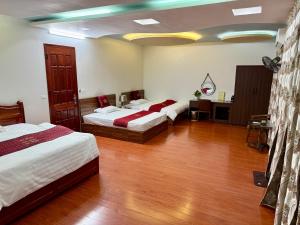 a bedroom with two beds and a wooden floor at Nhà nghỉ Quân An in Diện Biên Phủ
