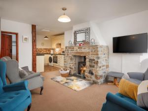 a living room with a stone fireplace with a flat screen tv at Beech Cottage in Launceston