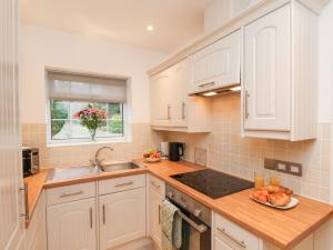 a kitchen with white cabinets and a bowl of fruit on the counter at Meadow Cottage in Scarborough