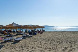 a beach with people sitting on chairs and umbrellas at Villa Panorama in Moúdhros