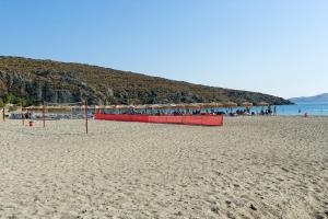 a beach with a volley ball net and umbrellas at Villa Panorama in Moúdhros