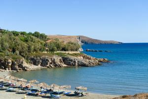 a beach with many chairs and umbrellas and the ocean at Villa Panorama in Moúdhros