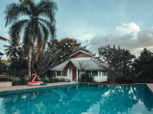 a pool in front of a house with a flamingo in the water at The Hideaway Village in Ban Mae Hi