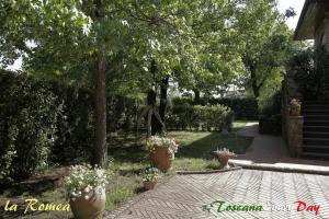 a garden with flower pots and trees and a walkway at La Romea in Altopascio +28 photos