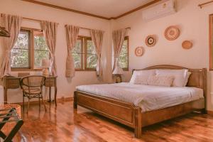 a bedroom with a bed and a desk and windows at The Hideaway Village in Ban Mae Hi