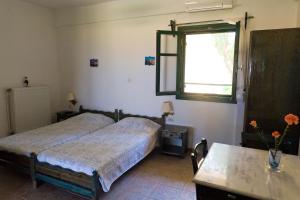 a bedroom with two beds and a table and a window at Villa Panorama in Moúdhros