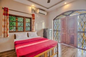 a bedroom with a red bed and stained glass windows at Calangute Sea Steps in Calangute