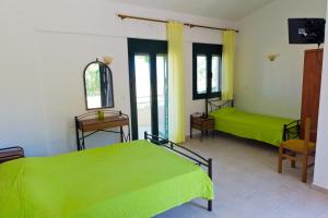 a room with two beds with green sheets at Villa Panorama in Moúdhros