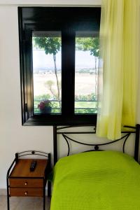 a bedroom with a green bed and a window at Villa Panorama in Moúdhros