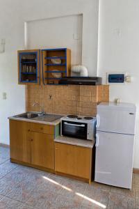 a kitchen with a sink and a stove and a refrigerator at Villa Panorama in Moúdhros
