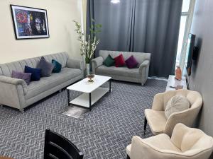 Apartment in Ajman في عجمان: غرفة معيشة بها كنبتين وطاولة وكراسي +22 صورة