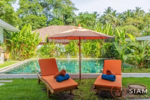 two chairs and an umbrella next to a swimming pool at Villa Sumalee 3Br Private Pool 8 mins to Beach in Koh Samui