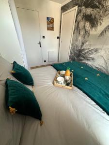 una cama con almohadas verdes y una bandeja encima. en T2 neuf- Balcon-Vue privilégiée Océan - Sud Ouest, en Les Sables-dʼOlonne