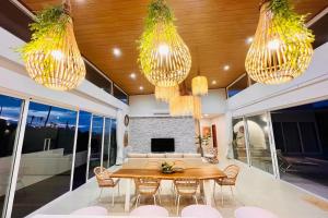 een eetkamer met een tafel en stoelen en kroonluchters bij Villa My Zen 4Br Private Pool & Walk to Beach in Chaweng Noi Beach