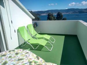 a pair of green chairs sitting on a balcony at Area da Barca Atico in Samieira