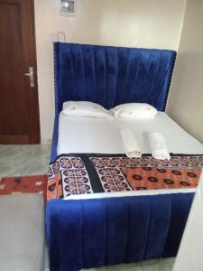 een bed met een blauw hoofdeinde en witte lakens en kussens bij Raicy Bnb in Bamburi