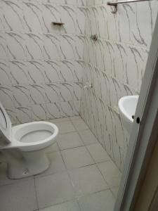 een badkamer met een wit toilet en een wastafel bij Raicy Bnb in Bamburi
