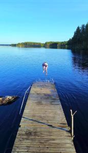 a person jumping off a dock into a body of water at Haven Islands incredible treehouse on private island in Torrflonäs