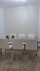 ein Esszimmer mit einem Tisch und weißen Stühlen in der Unterkunft Apartamentos Maria Cristina con parking gratis in Córdoba