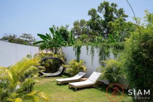a yard with two lounge chairs and plants at Villa Awaken 3br Private Pool in Bang Rak Beach