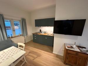 a kitchen with green cabinets and a television on the wall at Lütte Pension in Egestorf