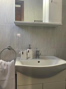 Un lavabo blanco en un baño con espejo. en Voupalou Apartments 2, en Chios