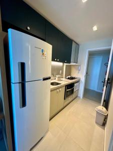 a white refrigerator in a kitchen with black cabinets at Flat beira mar em Tamandaré Carneiros - Kauai in Tamandaré