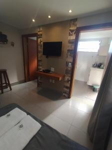 a living room with a television and a table at Flat Familiar em Capitolio Charlene Paiva in Capitólio