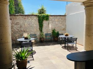 a patio with two tables and chairs and a stone wall at Casa De Los Remedios Morelia in Morelia