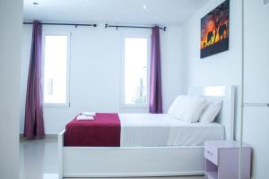 a white bedroom with a bed and two windows at Spacious & Serene 3-Bedroom Condo at Kai Villa in Accra