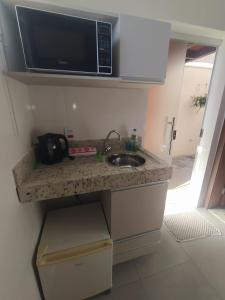 a kitchen counter with a sink and a microwave at Flat Familiar em Capitolio Charlene Paiva in Capitólio
