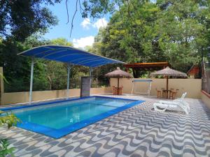 a pool with a blue umbrella and chairs and tables at Chalet del lago Don Asterio in Ciudad del Este
