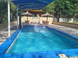 a large blue swimming pool with chairs and umbrellas at Chalet del lago Don Asterio in Ciudad del Este