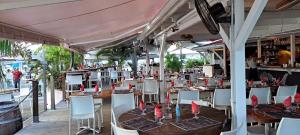 a dining room with tables and white chairs and tablesearcher at Superbe studio avec Piscine, au coeur de la Marina! Village Soleil ! Proche Aéroport & Ferry in Le Gosier