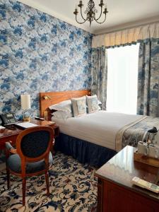 a bedroom with a bed and a desk with a chair at London Lodge Hotel in London