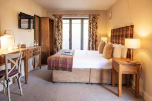 a hotel room with a bed and a desk and a desk at The White Hart, Wroughton in Swindon