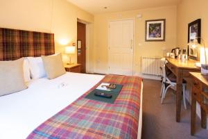 a hotel room with a bed and a desk and a desk at The White Hart, Wroughton in Swindon