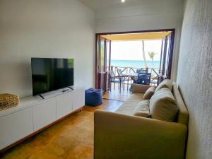 a living room with a couch and a flat screen tv at Cumbuco Penthouse - Som do Mar - Pé Na Areia - Ocean View - Ar Condicionado, perto do centro, 2 dormitórios, piscina, cozinha in Cumbuco