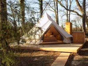 a bed in a tent in the woods at Tente avec jacuzzi vue lac 1 in Le Vigeant