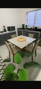 a table and chairs in a kitchen with a plant at Apto Novo Jardim Rosinha 04 in Sao Paulo