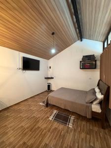 a bedroom with a bed and a flat screen tv at Chalé Primavera em Gonçalves in Gonçalves