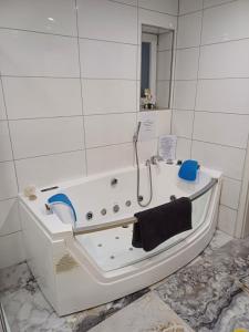a white bath tub in a white tiled bathroom at Ferienwohnung Unterm Rappenfels in Hinterweidenthal +23 photos