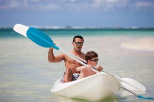 a man and a boy on a surfboard in the water at The Residence Mauritius in Belle Mare