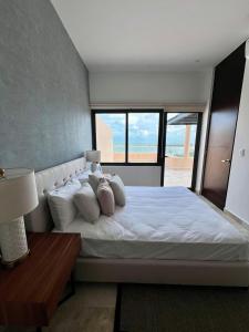 a bedroom with a large white bed with a window at Penthouse Navela 405 by Cercana in Telchac Puerto +19 photos