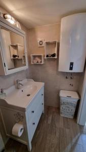 a bathroom with a sink and a mirror and a toilet at Apartman Manuela in Pag +18 photos